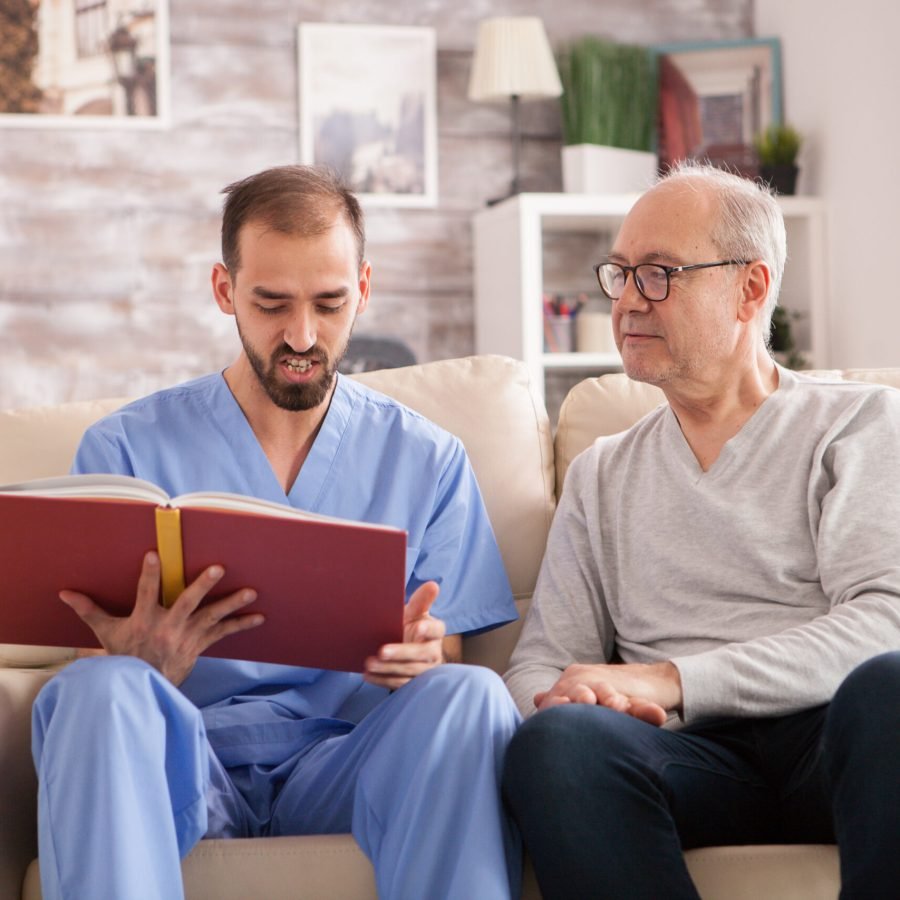 Happy senior woman in nursing home while doctor is reading a book.